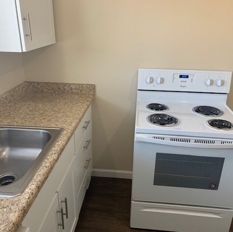 A white stove sits next to a sink in a kitchen.